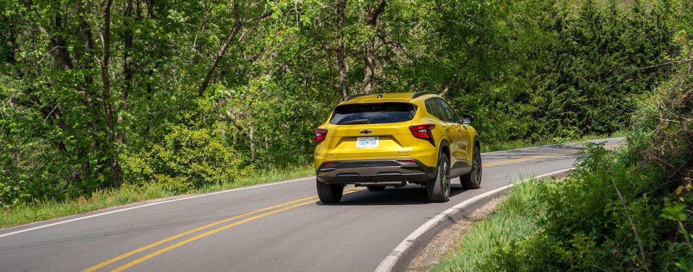 A yellow 2024 Chevy Trax ACTIV is shown from the rear at an angle after leaving a dealer that has Chevy Trax for sale in Dallas.