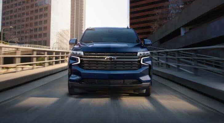 Head-on view of a blue 2023 Chevy Tahoe driving in a city.