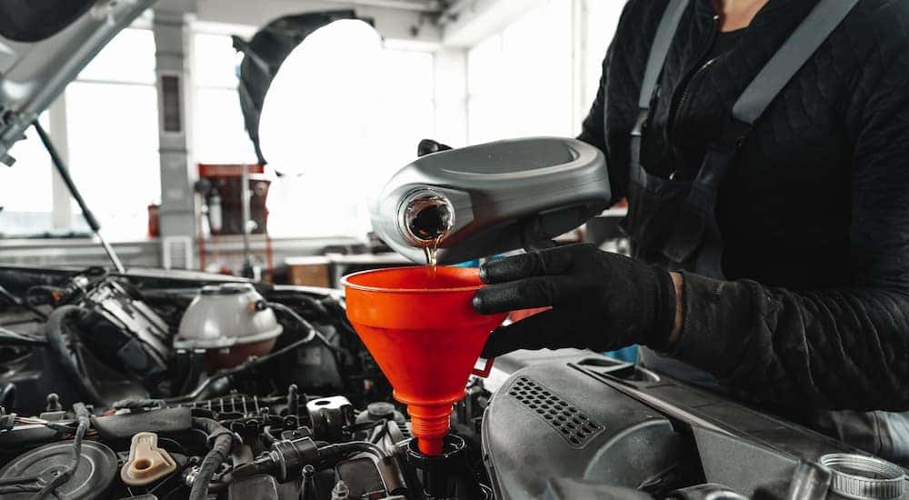 A mechanic pouring new oil into a car's engine.