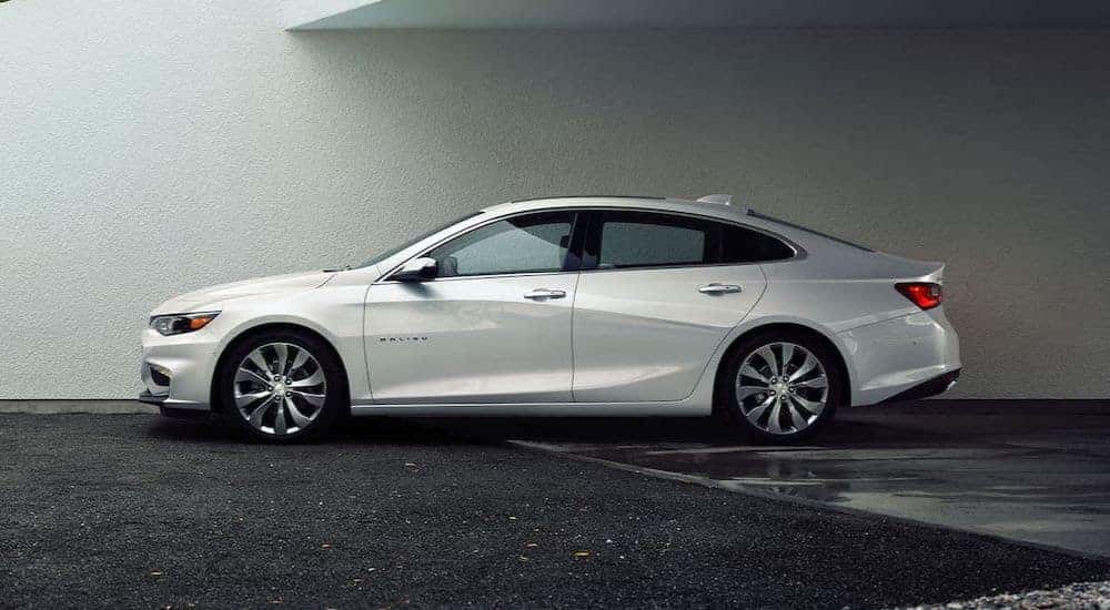 A white 2016 Chevy Malibu for sale in Dallas is shown parked on a wet ground.