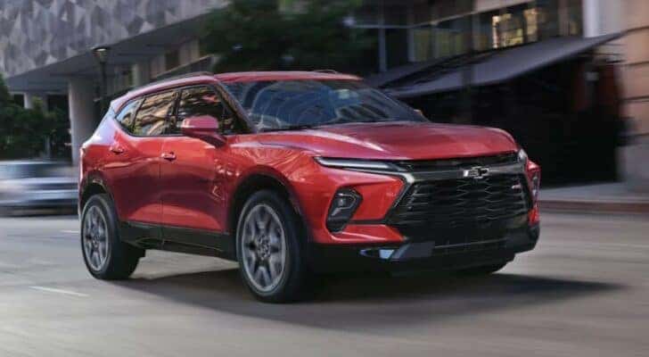 A red 2024 Chevy Blazer RS is shown driving to view a Chevy Blazer for sale.