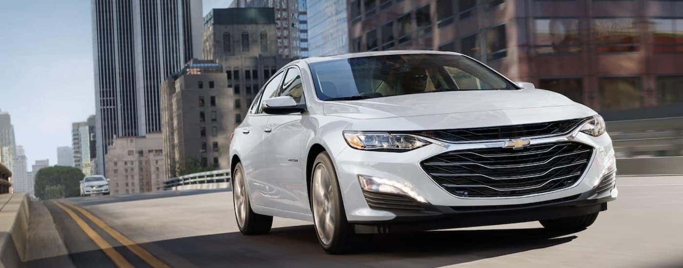 A white 2022 Chevy Malibu driving in a city.