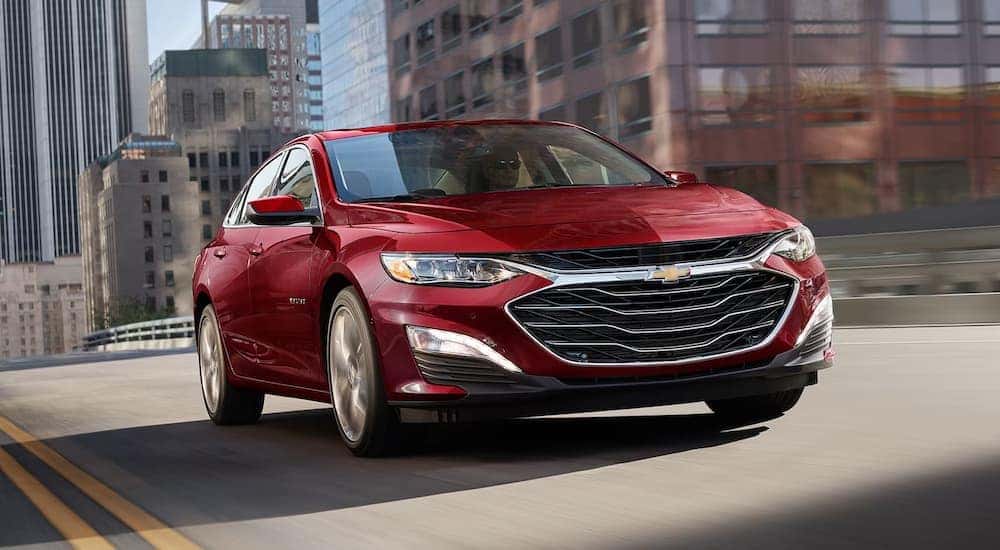 A red 2024 Chevy Malibu for sale in Columbus driving over a bridge.