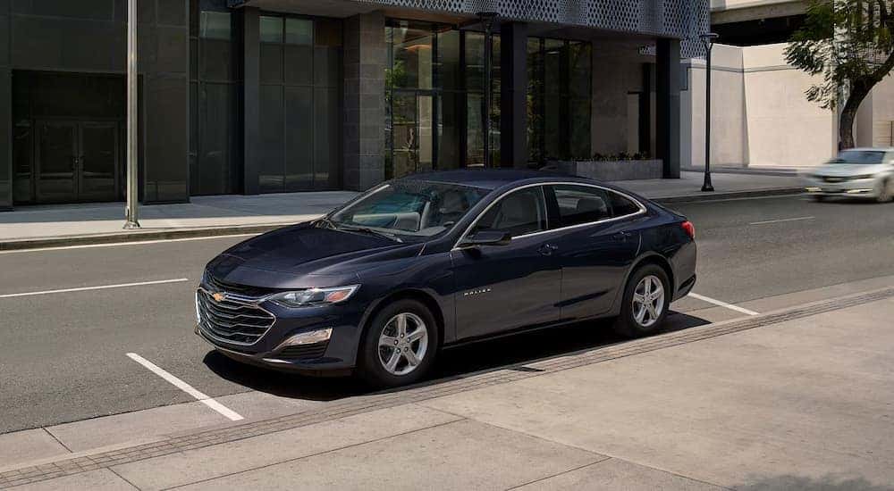 A black 2024 Chevy Malibu parked on a city street.
