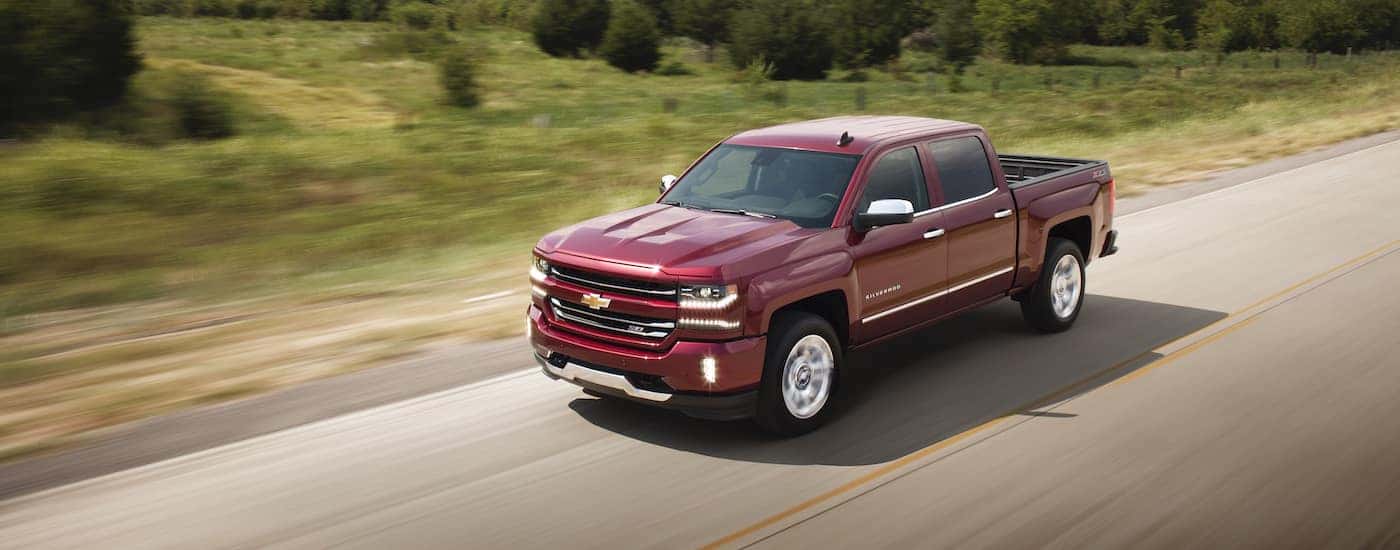 A red 2018 Chevy Silverado 1500 is shown driving on a highway.