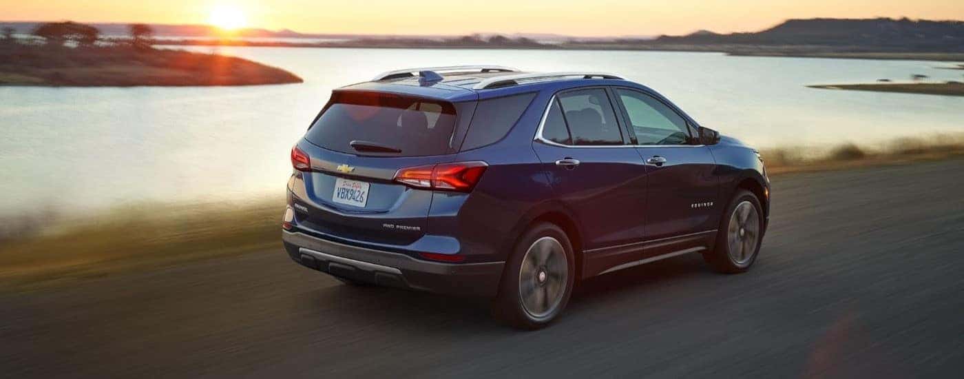 A blue 2022 Chevy Equinox Premier driving by a lake.