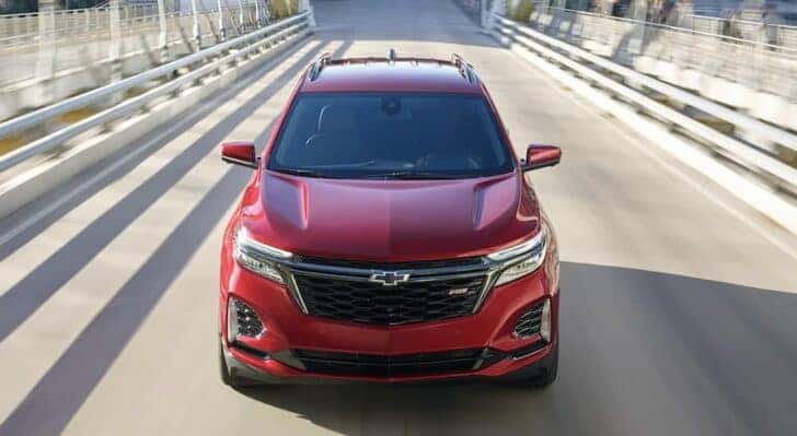 A red 2022 Chevy Equinox RS is shown driving on a bridge.