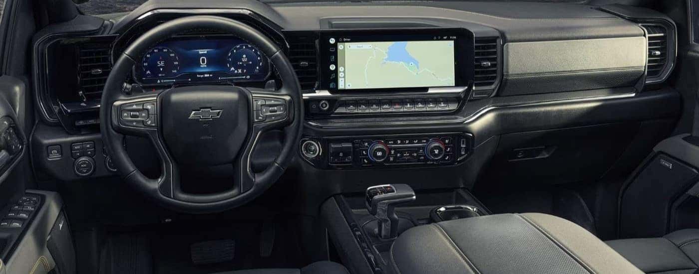 The black interior of a 2022 Chevy Silverado 1500, including the steering wheel and dashboard interface.