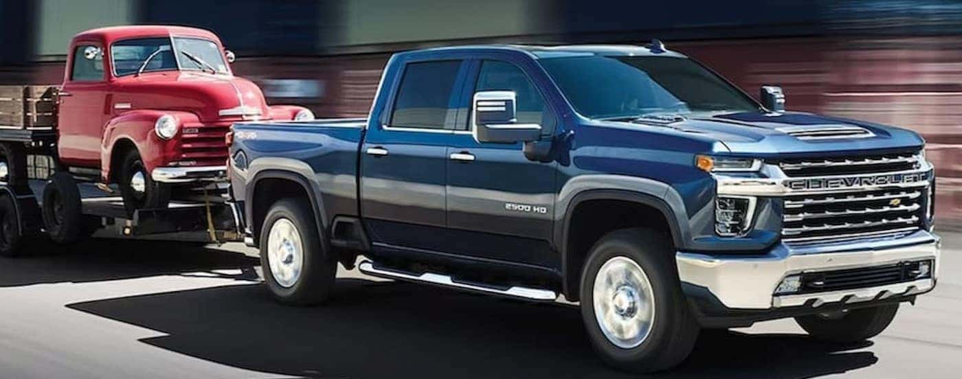 A blue 2023 Chevy Silverado 2500 HD is shown towing a trailer.