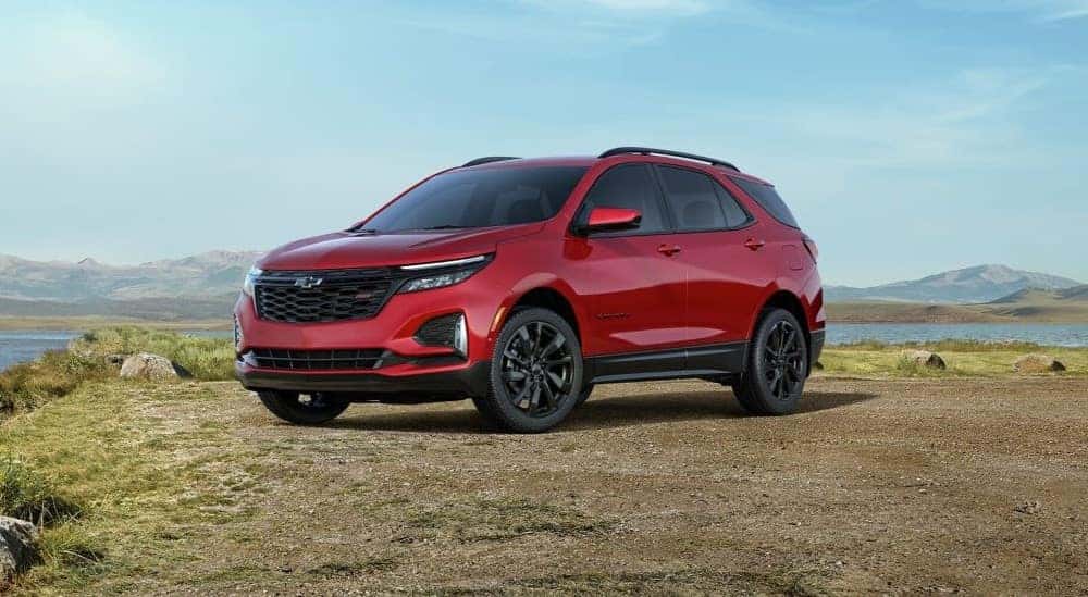 A red 2024 Chevy Equinox RS is shown parked near a lake.