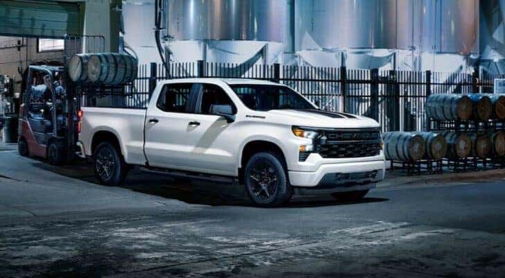 A white 2024 Chevy Silverado 1500 is shown parked near a distillery.