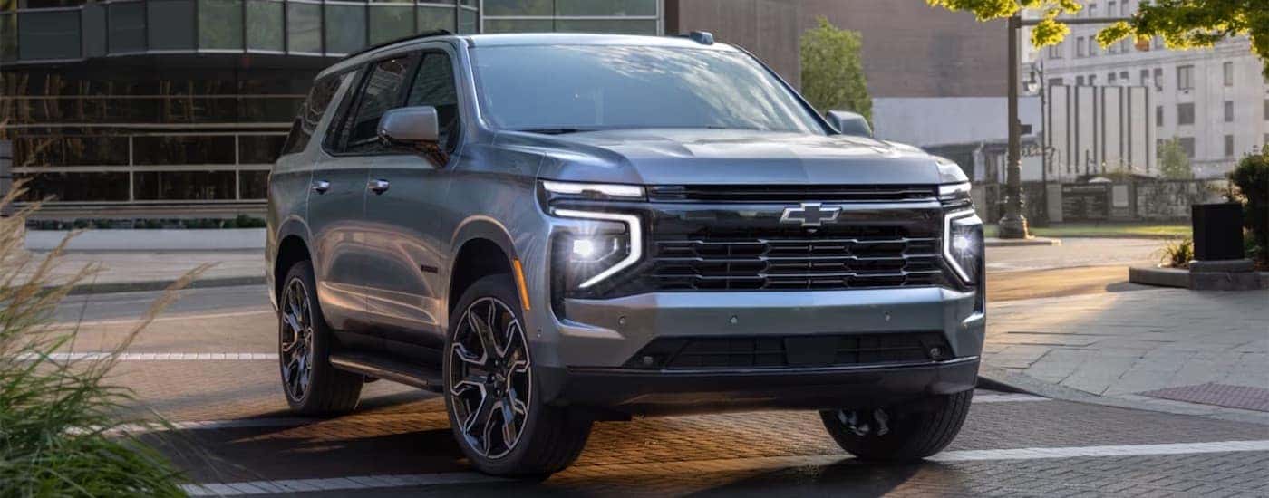 A grey 2025 Chevy Tahoe driving on a city street.