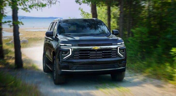 A black 2025 Chevy Tahoe driving through a forest.