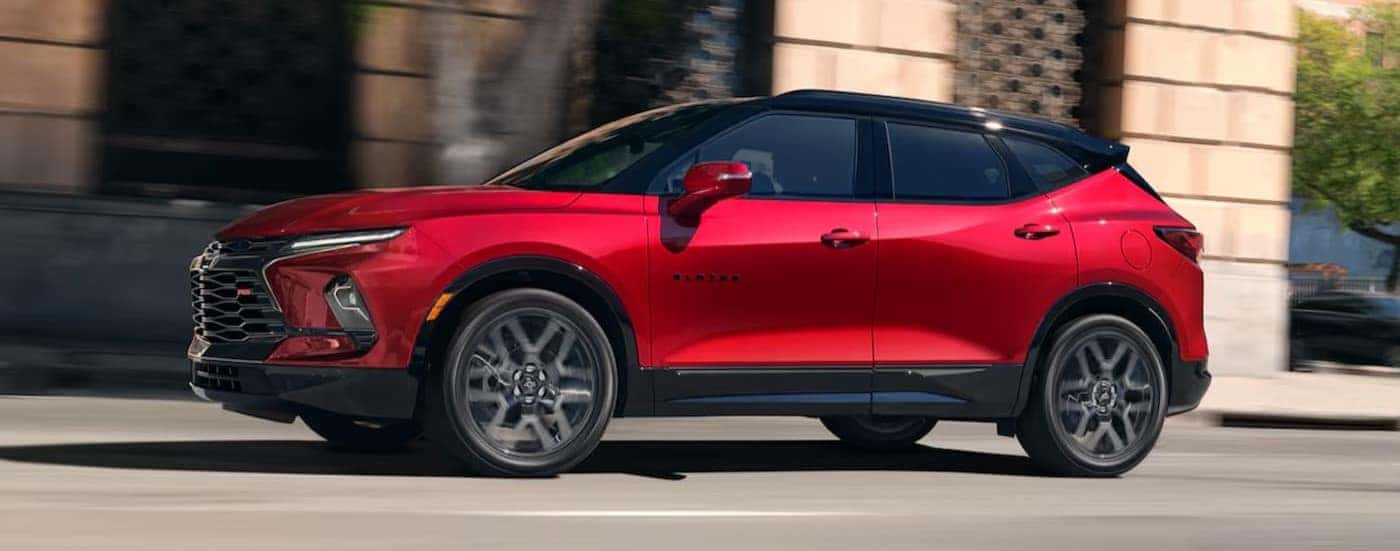 A red 2025 Chevy Blazer RS is shown driving on a city street.