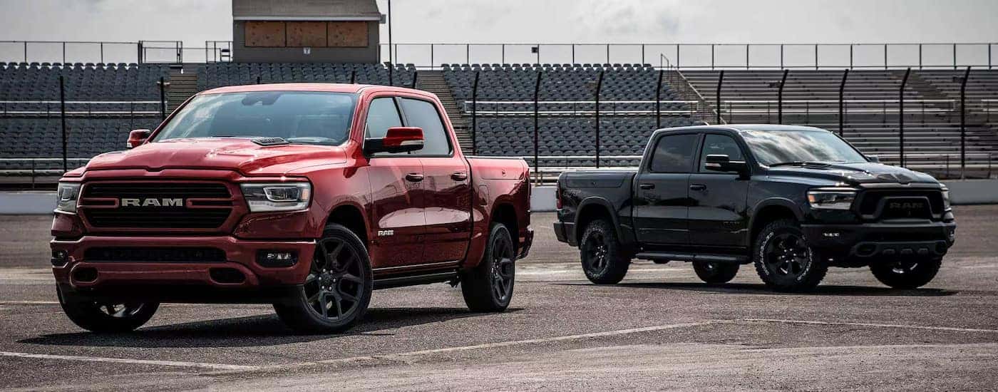 A red 2024 Ram 1500 Laramie GT and black Rebel GT Night Edition parked at a stadium.