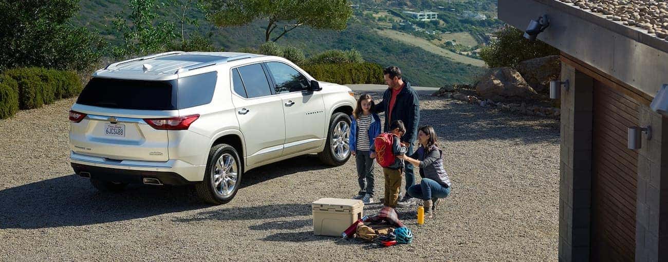 Rear angle view of a family standing beside a white 2021 Chevy Traverse for sale.