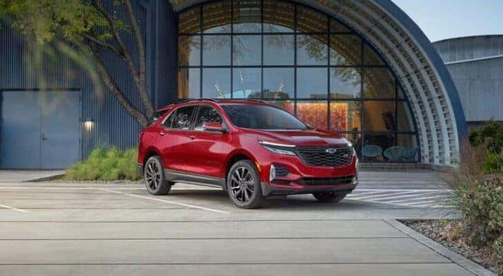 A red 2024 Chevy Equinox RS parked outside a building and angled right.