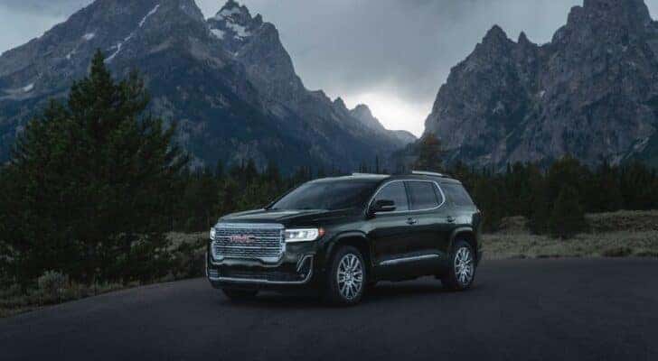A black 2023 GMC Acadia Denali parked in the mountains on a cloudy day.