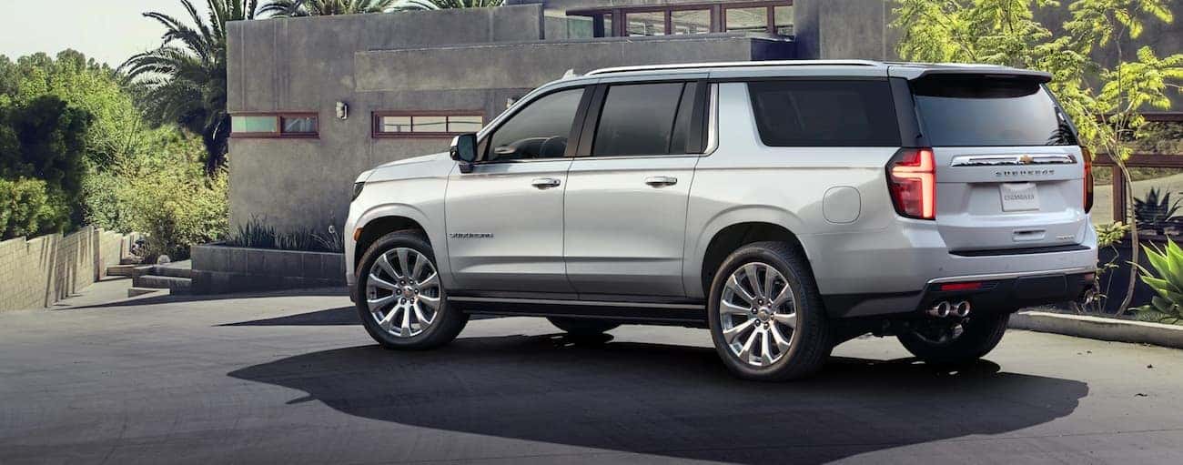 Rear angle view of a white 2021 Chevy Suburban parked outside a building.