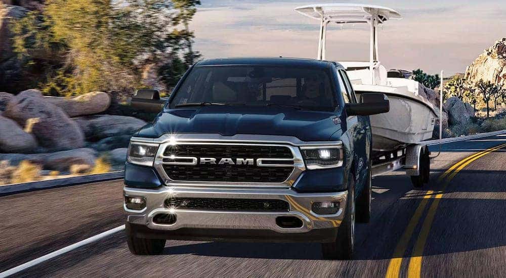 Front view of a blue 2024 Ram 1500 towing a boat.