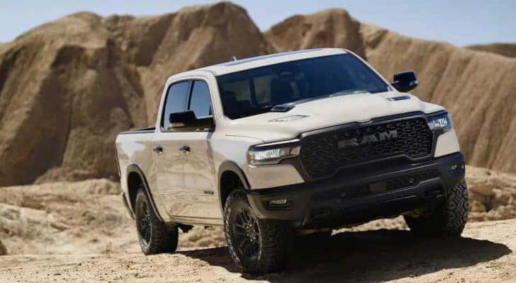 Right-angled view of a white 2024 Ram 1500 Rebel parked off-road in a desert.