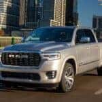 Left angled view of a grey 2025 Ram 1500 Tungsten driving through a city.