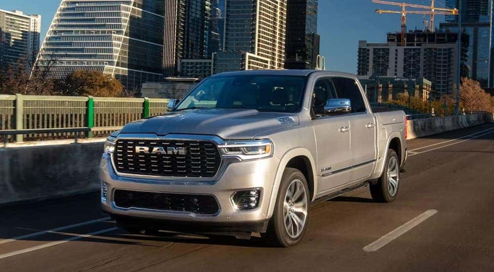 Left angled view of a grey 2025 Ram 1500 Tungsten driving through a city.