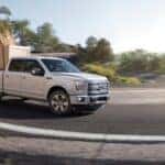 A white 2015 Ford F-150 is shown driving on a highway.