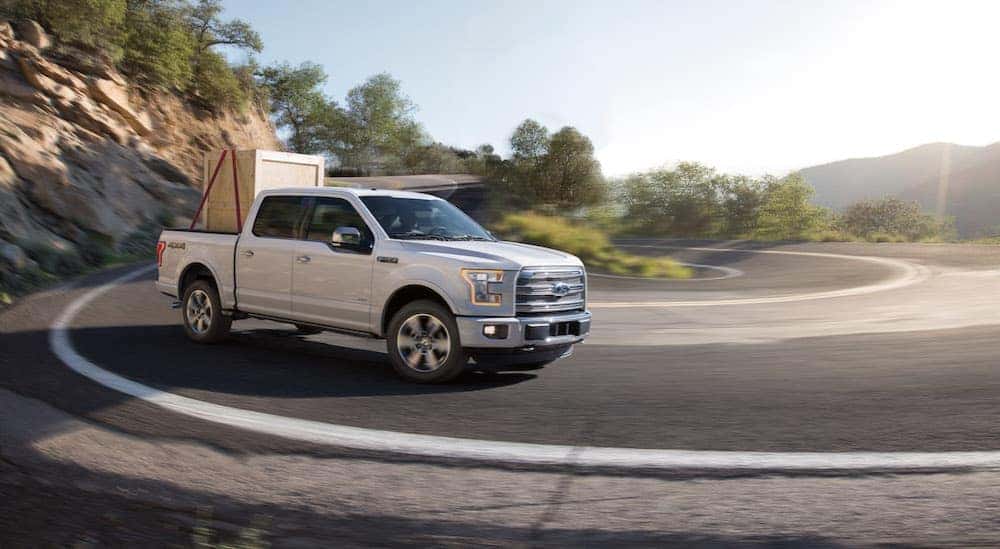 A white 2015 Ford F-150 is shown driving on a highway.