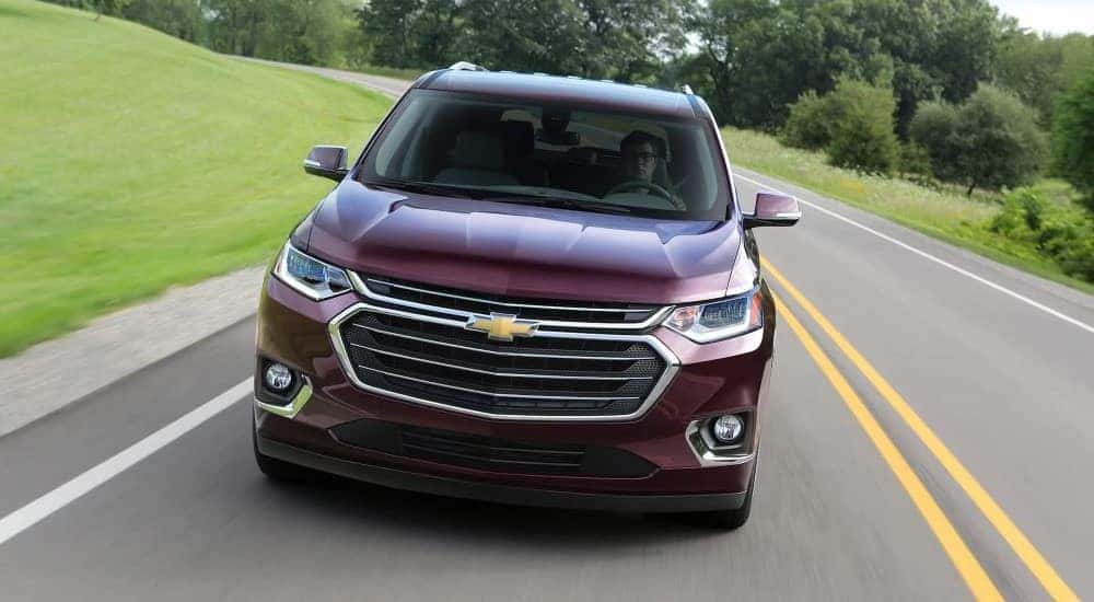 Front angle view of a red 2018 Chevy Traverse driving down a road.