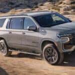 A silver 2023 Chevy Suburban Z71 is shown driving off-road.