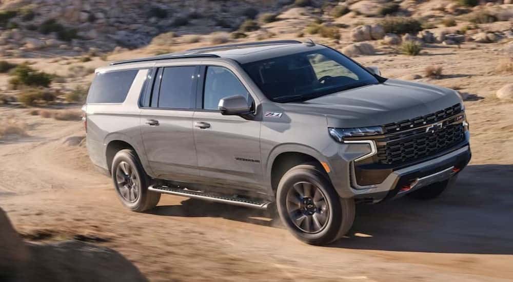 A silver 2023 Chevy Suburban Z71 is shown driving off-road.