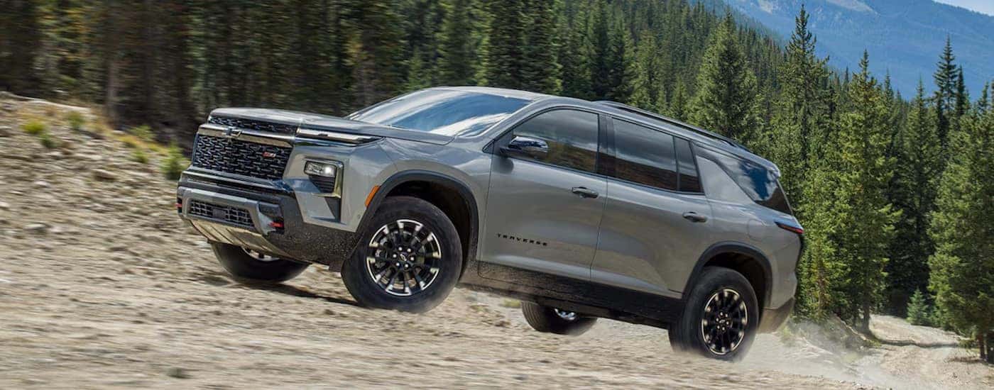 A silver 2024 Chevy Traverse Z71 is shown driving uphill.