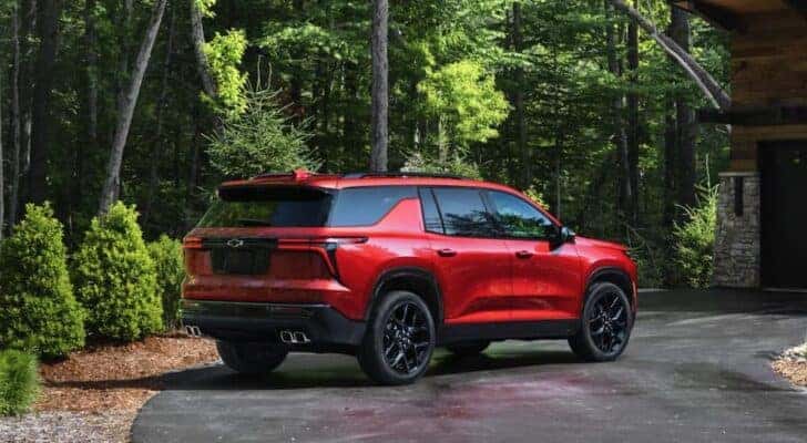 A red 2025 Chevy Traverse RS is shown parked on a driveway.
