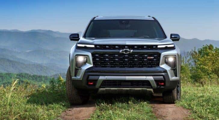 Head-on view of a silver 2024 Chevy Traverse Z71 parked on a grassy hilltop.