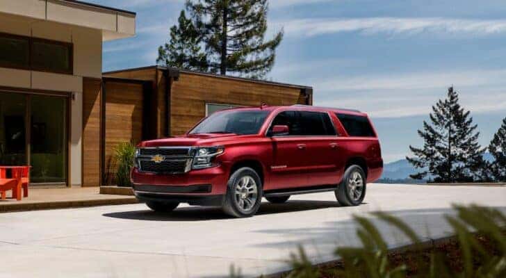 A red 2020 used Chevy Suburban for sale is parked in a driveway.