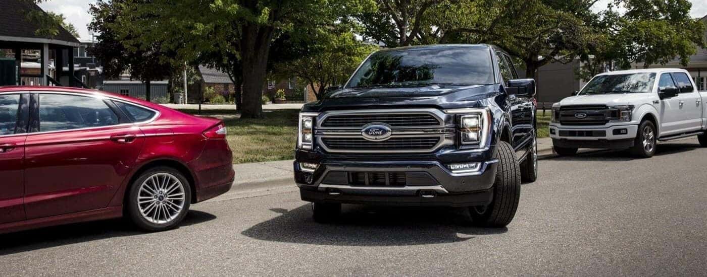 A black 2023 Ford F-150 pulling away from a sidewalk.