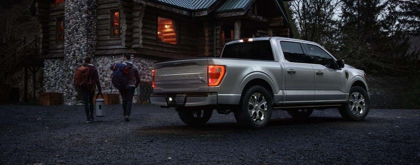 Rear view of a grey 2023 Ford F-150 Platinum parked near a cabin.