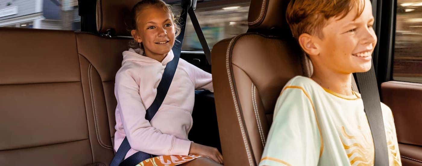 Two children are shown sitting in the rear seating area of a 2025 Chevy Suburban.