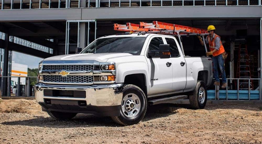 A white 2019 Used Chevy Silverado 2500 for sale is at a construction site.