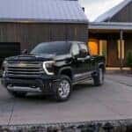 A black 2024 Chevy Silverado 2500 HD High Country is parked on a driveway.