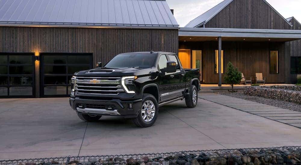 A black 2024 Chevy Silverado 2500 HD High Country is parked on a driveway.