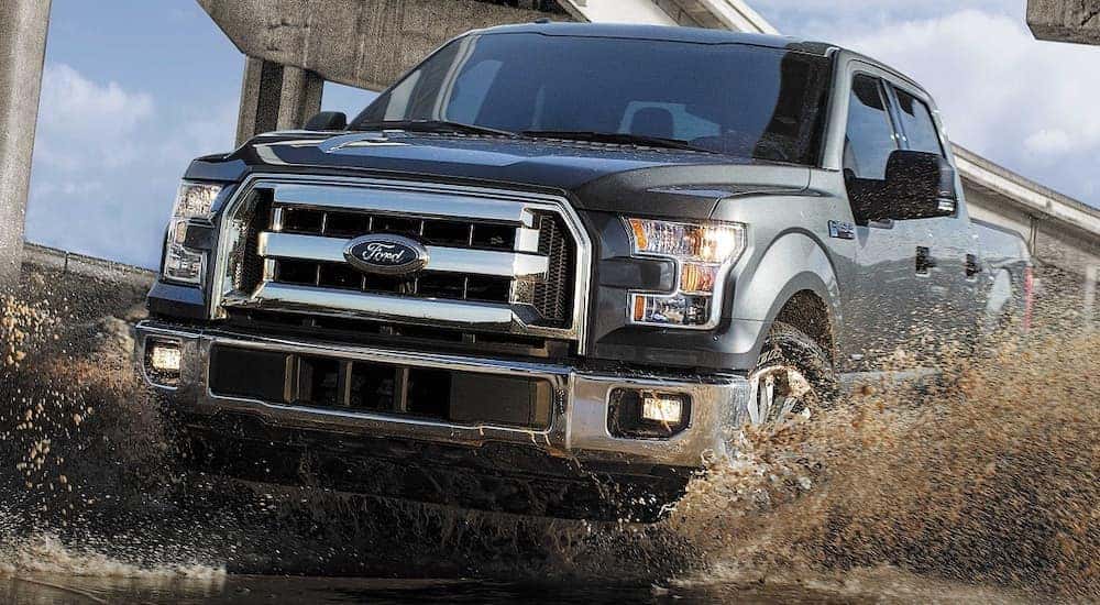 A grey 2017 Ford F-150 driving through mud.