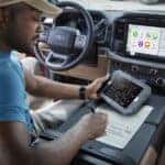 A man using a tablet in a 2021 Ford F-150 for sale in Fort Worth.