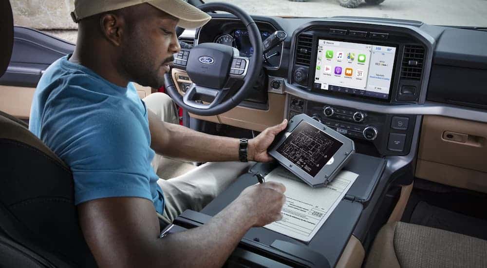 A man using a tablet in a 2021 Ford F-150 for sale in Fort Worth.