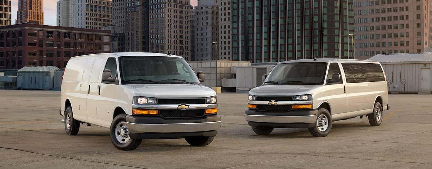 A duo of white 2025 Chevy Express 2500 vans parked on a parking lot.