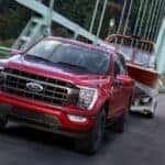 A red 2021 Ford F-150 for sale in Nashville towing a boat over a bridge.