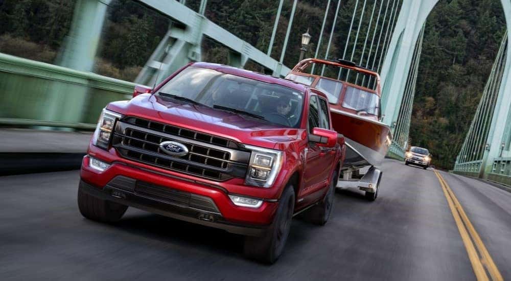 A red 2021 Ford F-150 for sale in Nashville towing a boat over a bridge.