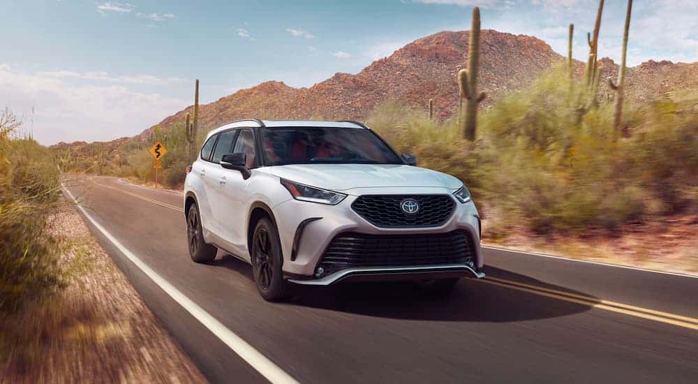A white 2023 Toyota Highlander XSE driving on an open road.