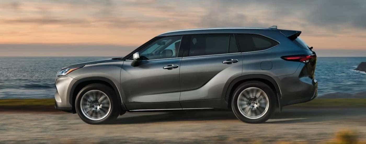A silver 2025 Toyota Highlander for sale in Columbus driving near water.